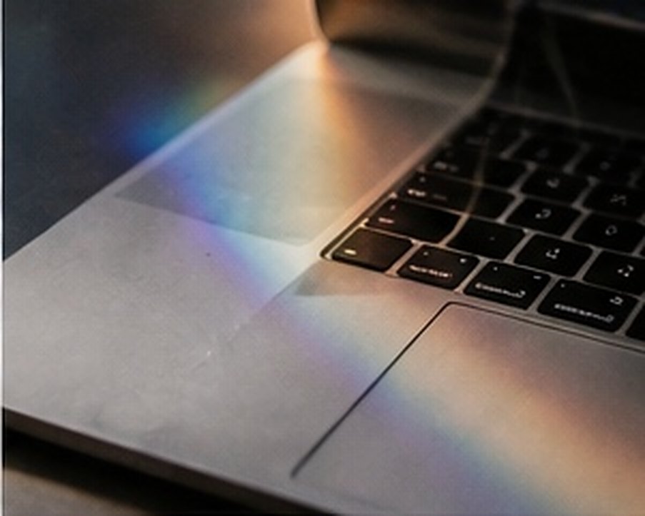 A rainbow of refracted light falling across a laptop keyboard