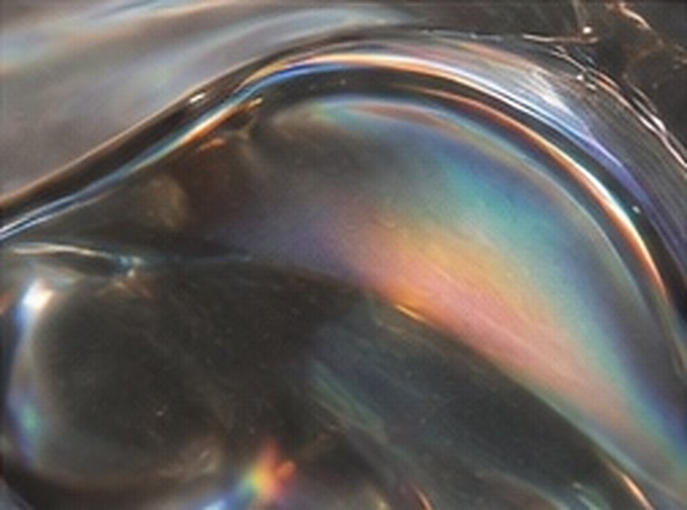 Rainbow light curving through a pool of liquid chrome