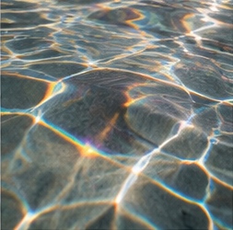 Sunlight rippling across the floor of a pool, with a faint rainbow at the edges of the light